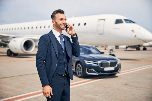Businessman standing in front of an aircraft Handsome man in a suit talking on the phone while standing in front of an airplane